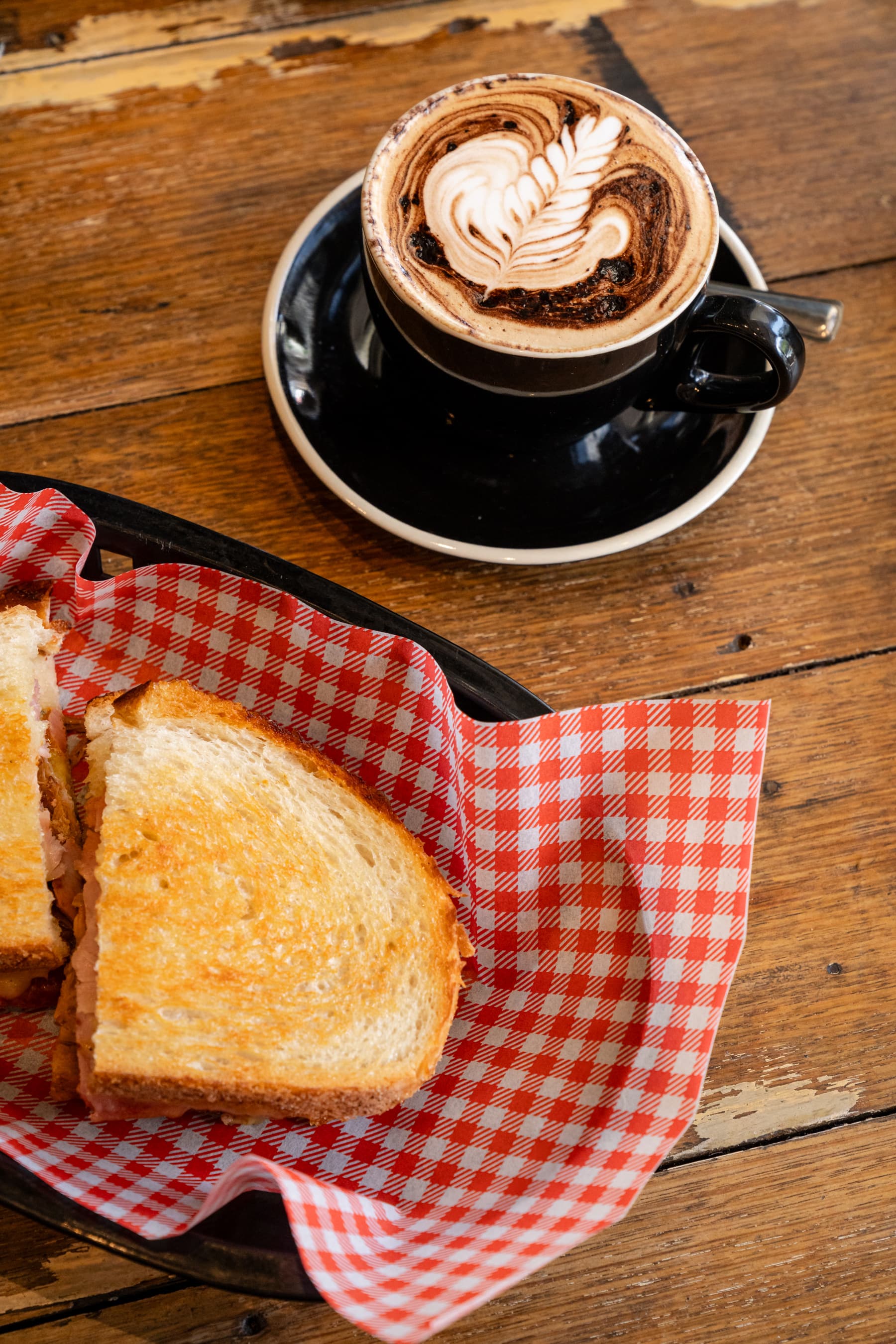 Mocha latte art beside a toasted sandwich