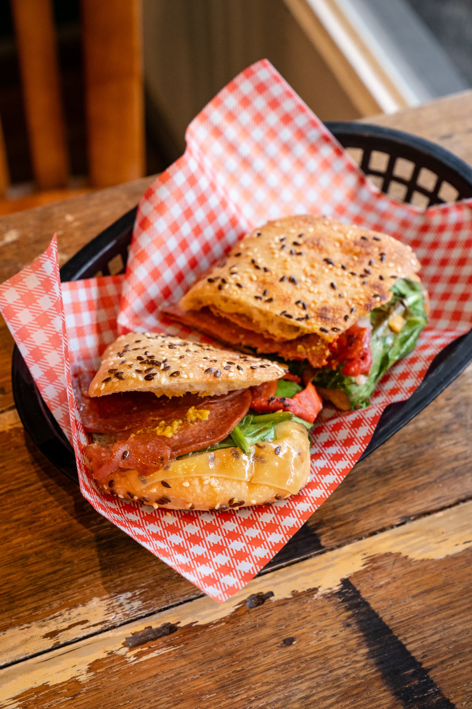 Seeded sandwich halves served in a basket on a timber table